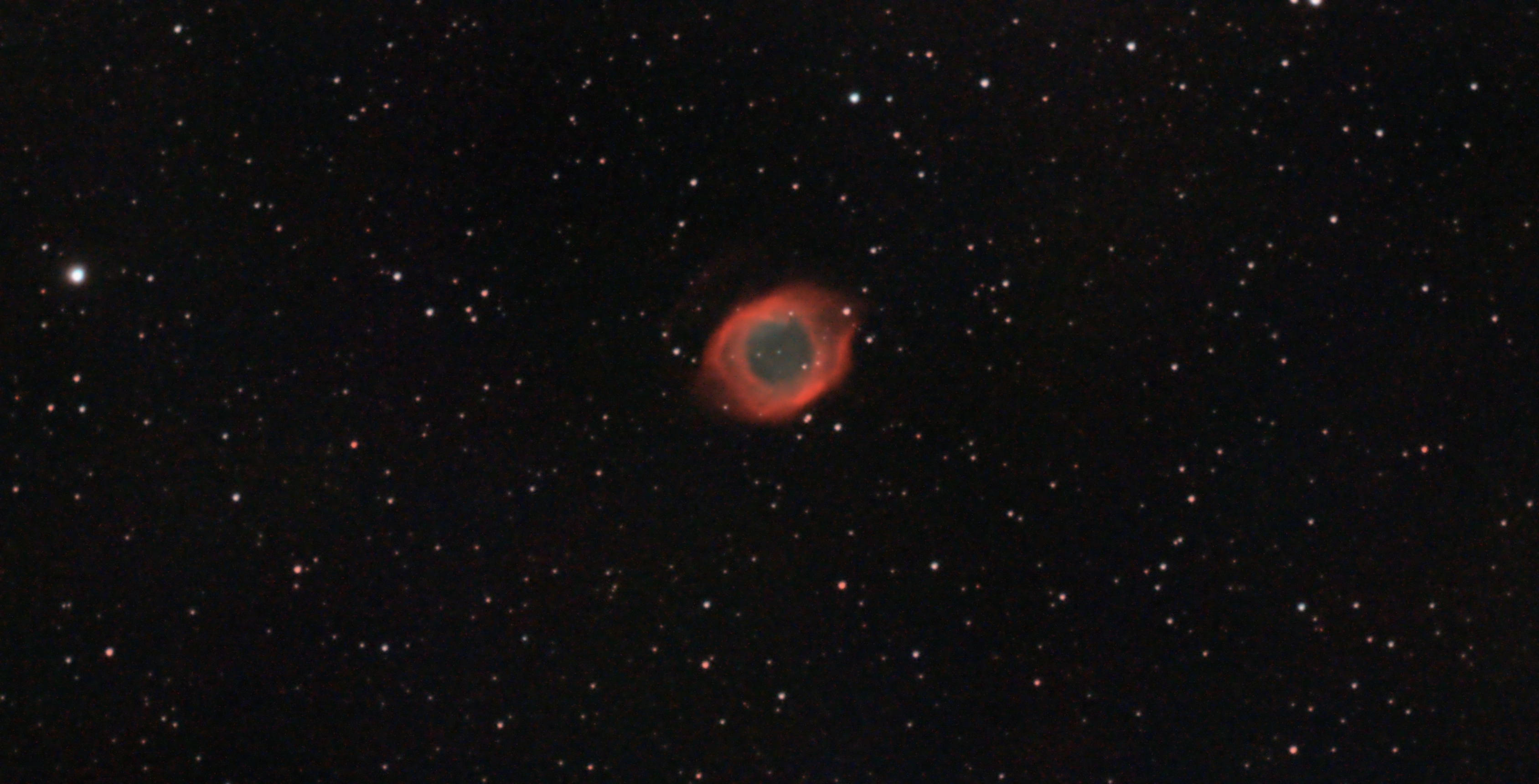 The Helix Nebula with a bright red ring around its blue-green center, surrounded by stars
